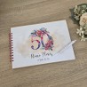 Libro de visitas artesanal con motivos florales en tonos pastel.